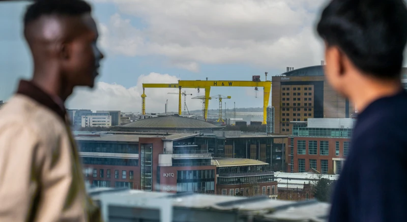 Employees looking out over the Belfast skyline from a Liberty IT office.