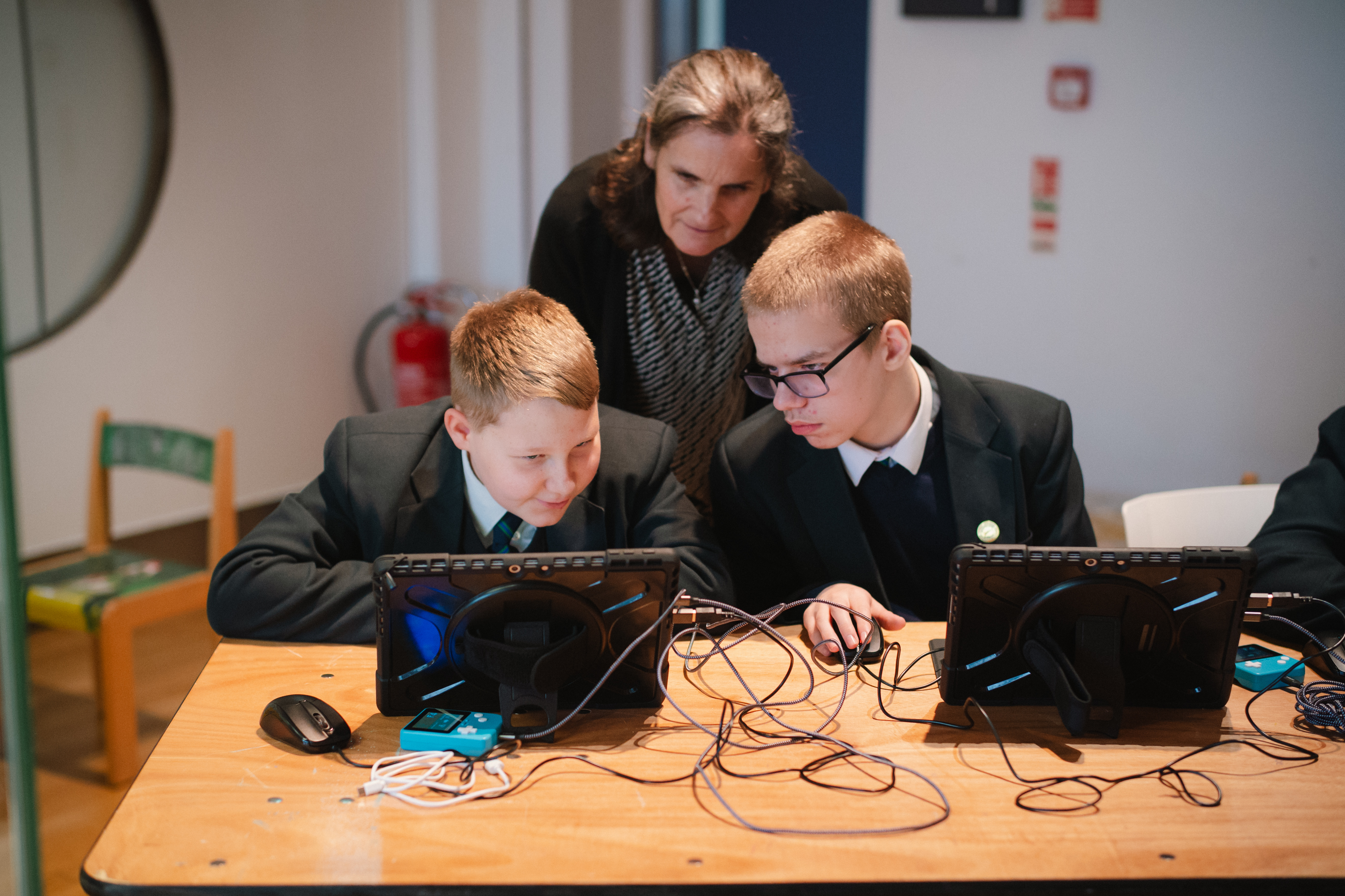 Two students taking part in a STEAM Studio session being assisted by their teacher