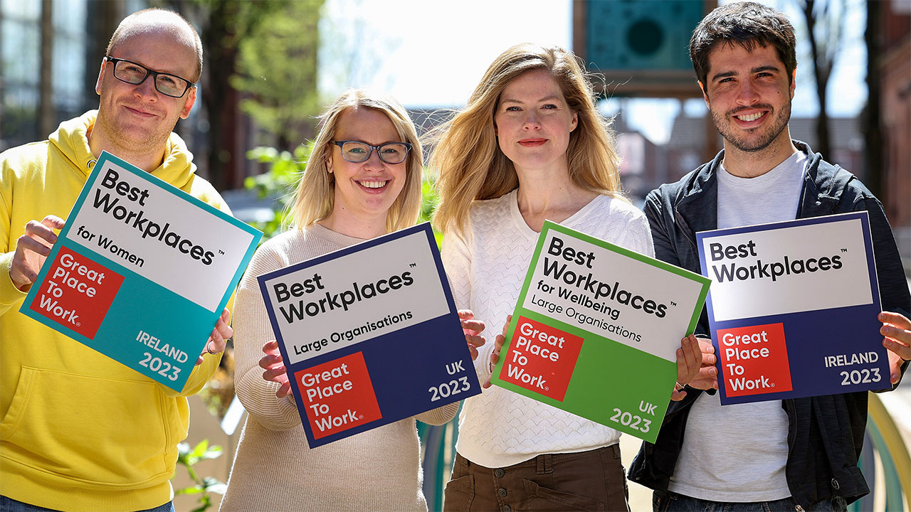 Photo with four Liberty IT employees (Solutions Engineer, Darryl Stacey; Engineering Manager, Clare Dalglish; Senior Director of Talent, Emma Mullan and Principal Engineer, Martin Roestorff) holding four Great Place to Work logos.