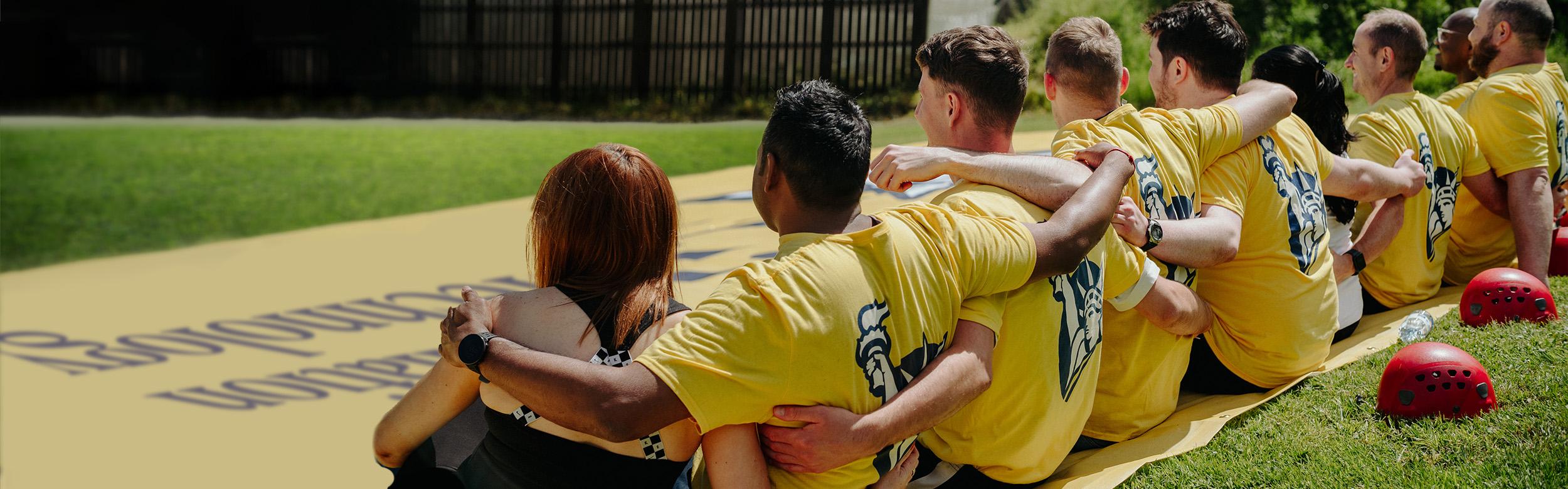 Row of people sitting on a yellow canvas sheet