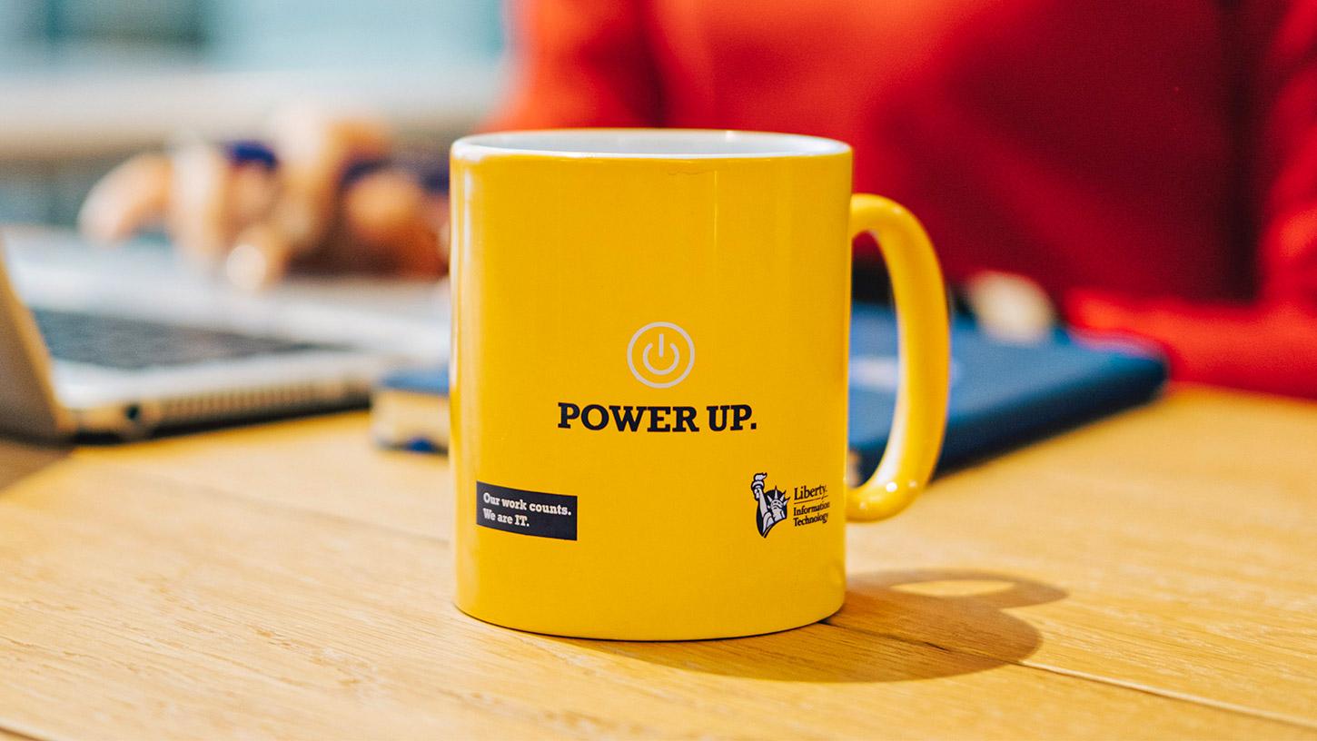 Photo of a yellow Liberty IT mug with the words Power Up
