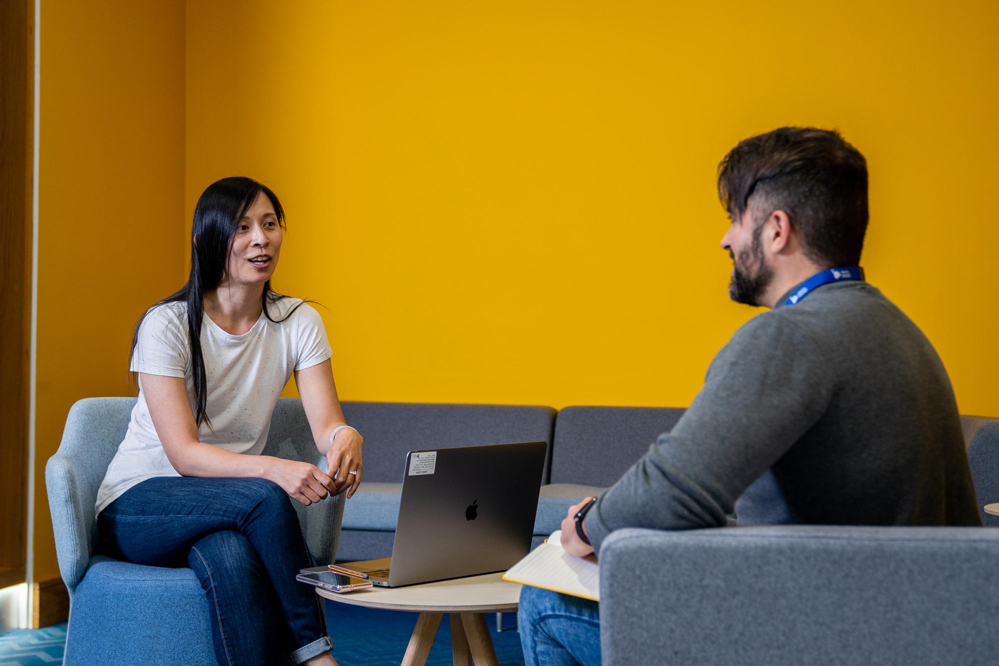 Photo of woman and man talking over laptop