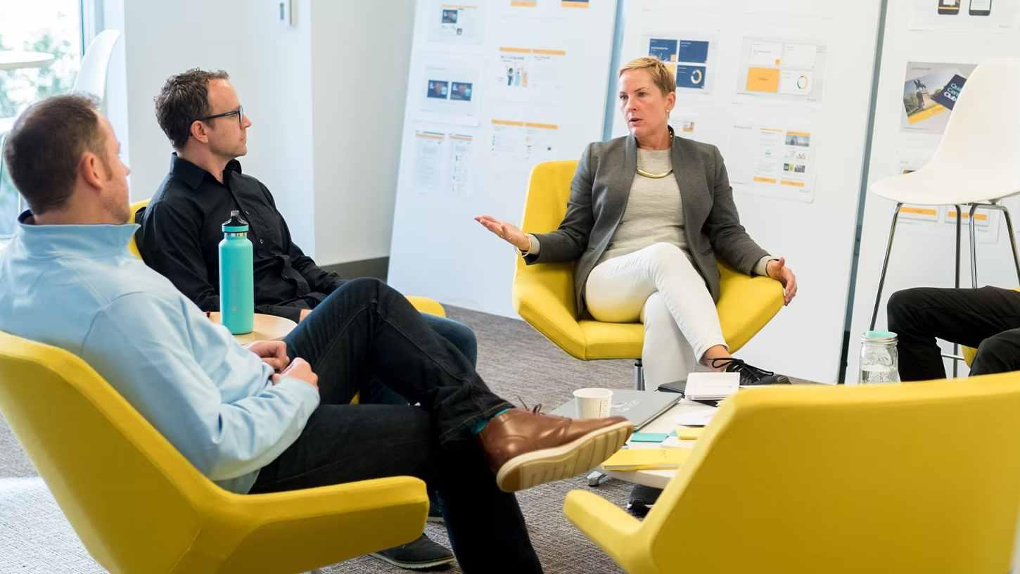 Two men and a woman talking on yellow chairs