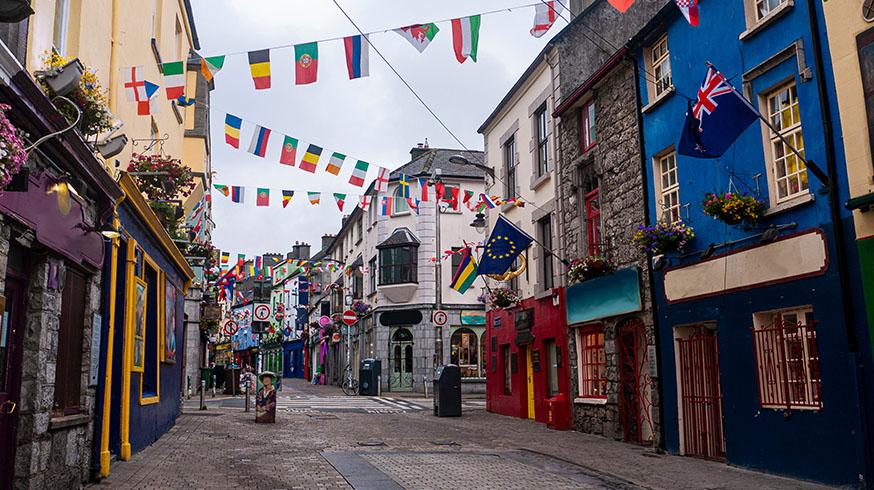 View of the main high street in Galway City with the brightly painted buildings and cobblestone streets on a cloudy day